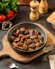 Deliciously cooked beef chunks served in a rustic bowl on a wooden board with fresh vegetables for a hearty meal