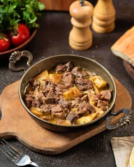 Savory beef stew served with potatoes on a rustic wooden table, surrounded by fresh ingredients and rustic decor
