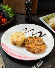 Delicious creamy chicken served with aromatic rice and fresh greens on a stylish plate in a cozy dining setting