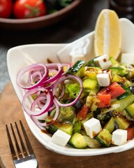 Fresh and colorful salad with cucumbers, tomatoes, red onions, and feta cheese served with a slice of lemon