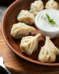 Flavorful dumplings served with creamy sauce on a wooden plate in a cozy restaurant setting
