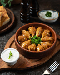 Delicious dumplings served with creamy sauce on a wooden table, perfect for sharing during lunch or dinner with friends and family