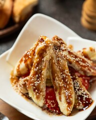 Delicious dessert of grilled bananas drizzled with sauce and topped with sesame seeds served in a cozy restaurant setting