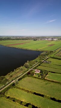 Aerial view of a rural landscape with a central road, water body, irrigated fields, and scattered houses. The scene highlights agricultural planning and natural integration.