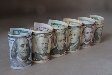 Rolled US dollar bills with American presidents lined up in row.
