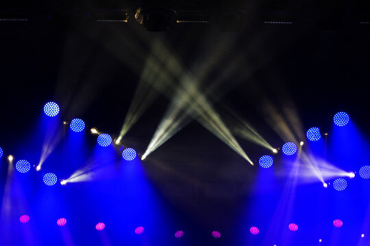 A stage with multiple blue and red lights is lit up. The blue lights are positioned on the left side of the stage, while the red lights are on the right side