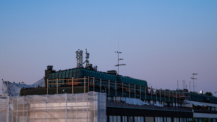 Jackdaws perched on a rooftop in the light summer night of Finland, with a clear twilight sky in the background.