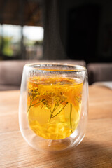 Herbal tea with flowers placed on a wooden table in a cozy setting during the afternoon