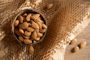 Almonds in a wooden bowl on textured fabric showcasing a rustic kitchen setting with natural light