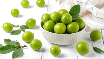 Fresh green plums in a bowl on a white wooden table