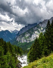 Obraz premium Alpine valley with a rushing river under a stormy sky
