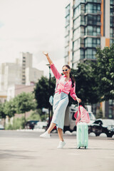 Lovely woman enjoying a sunny day in the city carrying a vibrant suitcase showcasing cheerful travel vibes