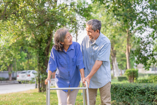 asian senior married couple enjoy relaxing and rehabilitation in nature with husband,older disabled person walking in the park