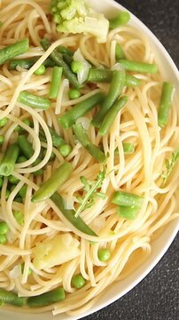 Spaghetti vegetables green peas, broccoli, string beans, kohlrabi vegetarian pasta tasty snack fresh delicious gourmet food background on the table rustic top view copy space vegan food