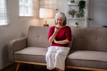 Obraz premium Asian older woman speaks smartphone voice message home living room couch modern technology senior communication connection lifestyle