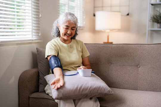 Older Asian woman measures blood pressure at home for wellness and personal health monitoring self care during retirement