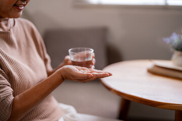 Older Asian woman takes daily medicine health wellness home comfort routine self care healthy lifestyle