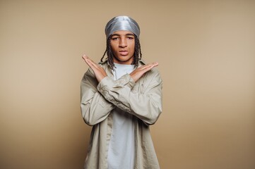Young person making a gesture of defiance with crossed arms against a simple background