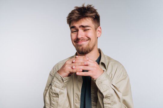 Smiling young man with tousled hair and a playful expression in a light background setting