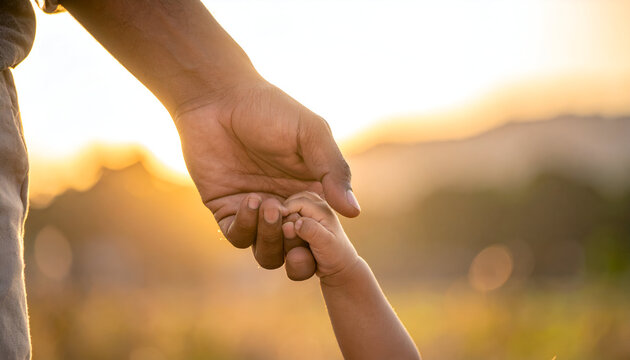 Childs Hand Held by Adult in Sunset.