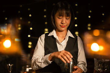Professional female bartender preparing alcoholic drinks in a bar