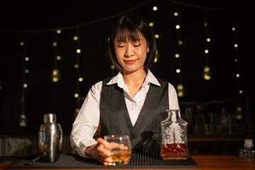 Professional female bartender preparing alcoholic drinks in a bar