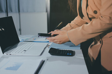 Close-up of businessman's hands making notes, mobiles, chart, desk, office