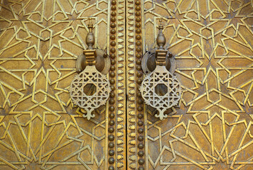 Fez, Morocco. Detail of a highly intricate paneled brass door and door knocks with Islamic symbols.