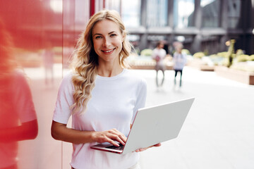 Smiling woman working on laptop in urban area