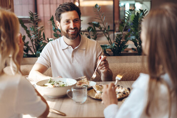 Happy man having lunch with friends in restaurant