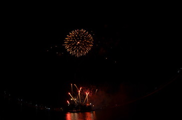 Golden Fireworks Exploding in Night Sky over River Festival Celebration