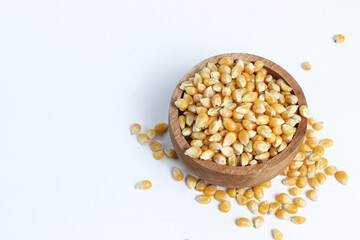 Raw corn kernels or popcorn in a small wooden bowl. Isolated on a white background.