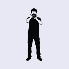 Silhouette of a person standing and holding a camera to take a photograph against a plain background
