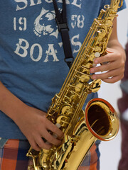 Human hand holding playing a saxophone close up with another saxophone in the background during musiclessons
