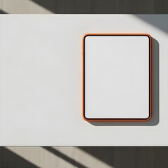 This image shows a tablet with a white screen off, orange case placed on a minimalist table with no other devices or objects cluttering it up, leaving an empty space on the left side, top view, natura