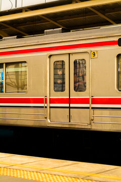 Close-up of a modern commuter train with striking red stripes at a station platform, featuring a passenger inside giving a clear thumbs-up, symbolizing efficient and positive urban travel experiences.