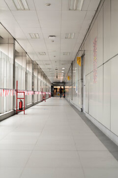 Sleek, minimalist walkway in a contemporary building, showcasing clean lines, ample lighting, and a sense of depth. Perfect for illustrating themes of architecture, public transit, and movement.
