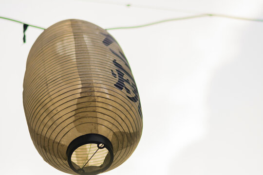 Traditional Japanese paper lantern with distinct black characters, perfect for cultural event promotions, travel themes, or Asian-inspired decor backgrounds, offering ample copy space.