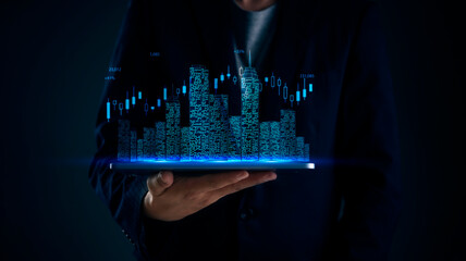 Business person holds hologram city above device to monitor real estate stock trends with data visualization candlesticks for smart city development planning and financial technology insights.