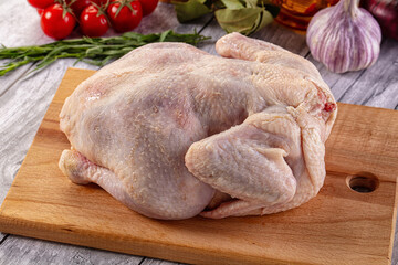 Raw whole chicken over board
