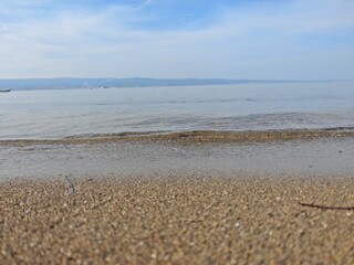 View of calm sea blending with sandy shore at midday under a clear blue sky