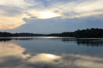 Beautiful sunset sky with soft clouds reflecting on calm lake surface