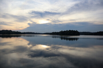 Calm lake water reflecting cloudy sunset sky