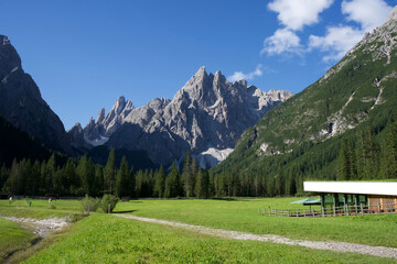Majestic mountain landscape with lush green meadow and clear blue sky in the Dolomites, Italy showcasing natural beauty