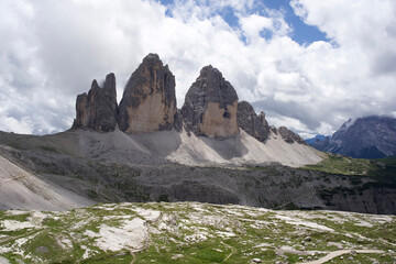 Majestic Dolomites mountain range with towering peaks and lush green valley under a dramatic cloudy sky