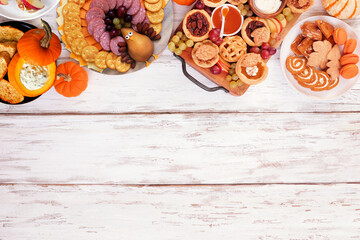 Thanksgiving appetizers, sweets and grazing boards. Above view top border on a white wood background. Pumpkin and apple snacks, pies, turkey cheese platter, desserts.
