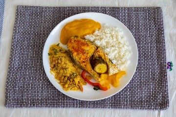 Traditional Brazilian fish moqueca with fresh yellow hake fish fillets, Cynoscion acoupa, with farofa, pirão and white rice. Pescada amarela and dende oil.