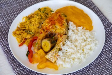 Traditional Brazilian fish moqueca with fresh yellow hake fish fillets, Cynoscion acoupa, with farofa, pirão and white rice. Pescada amarela and dende oil.