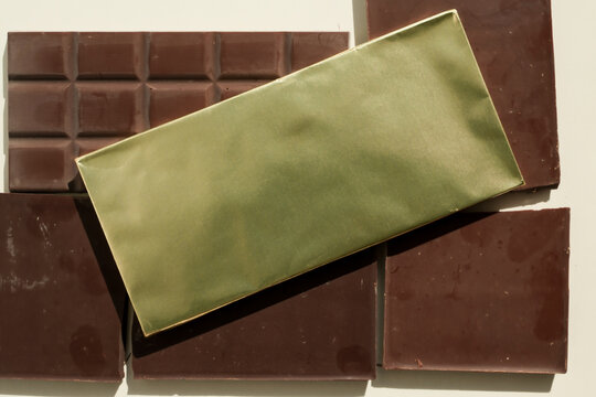 Chocolate bar in yellow foil paper on an unwrapped chocolate bars background. Copy space.
