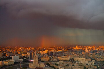 Clouds with rain and rainbows over the city in summer